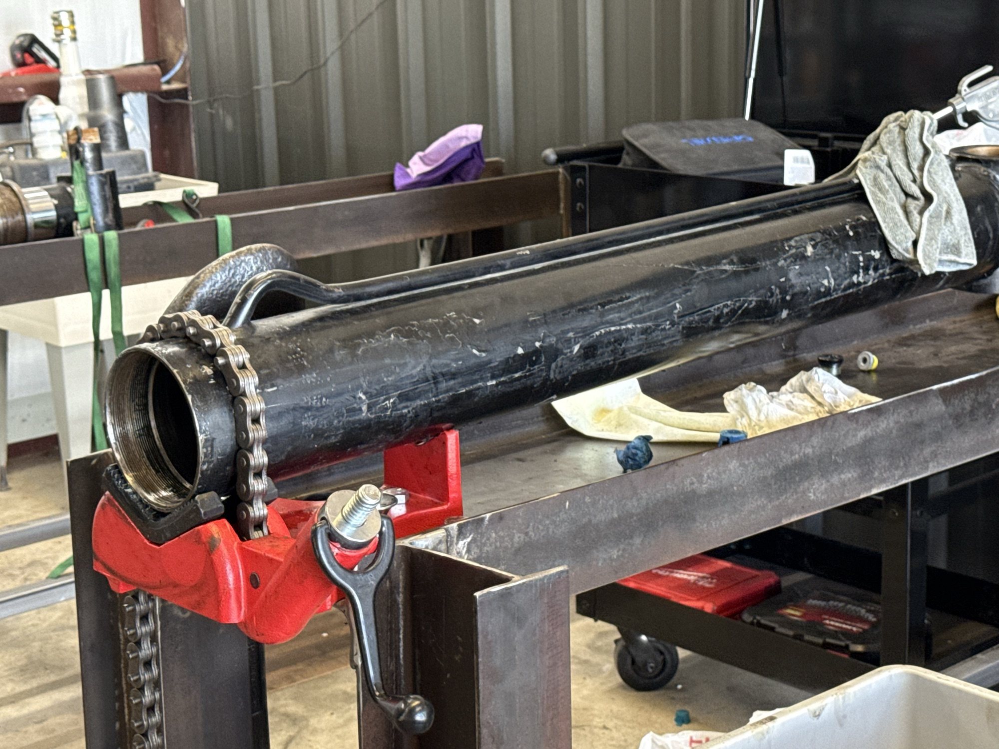 Large black hydraulic cylinder staged for repair