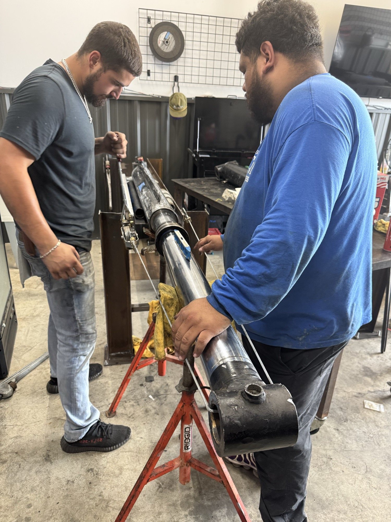 Technicians inspecting a heavy hydraulic cylinder assembly